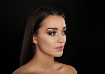 Portrait of young woman with eyelash extensions and beautiful makeup on black background