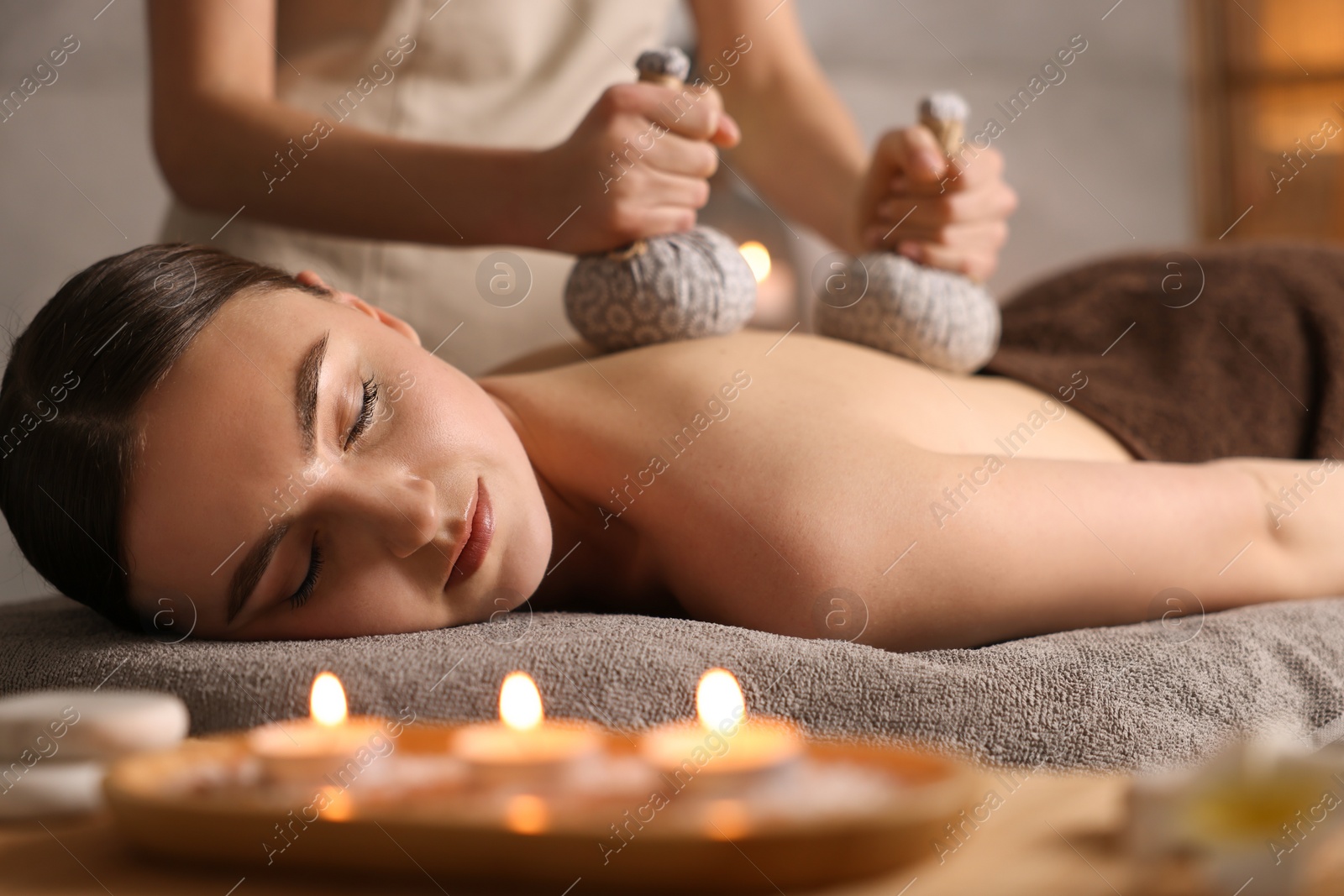 Photo of Spa therapy. Beautiful young woman lying on table during herbal bag massage in salon