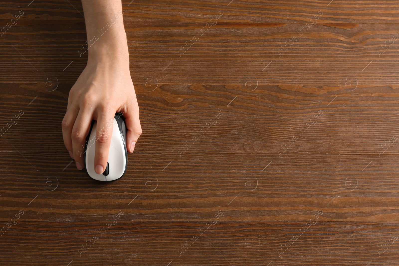 Photo of Woman using computer mouse on wooden background, top view. Space for text