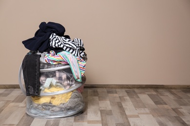 Photo of Laundry basket with dirty clothes on floor indoors. Space for text