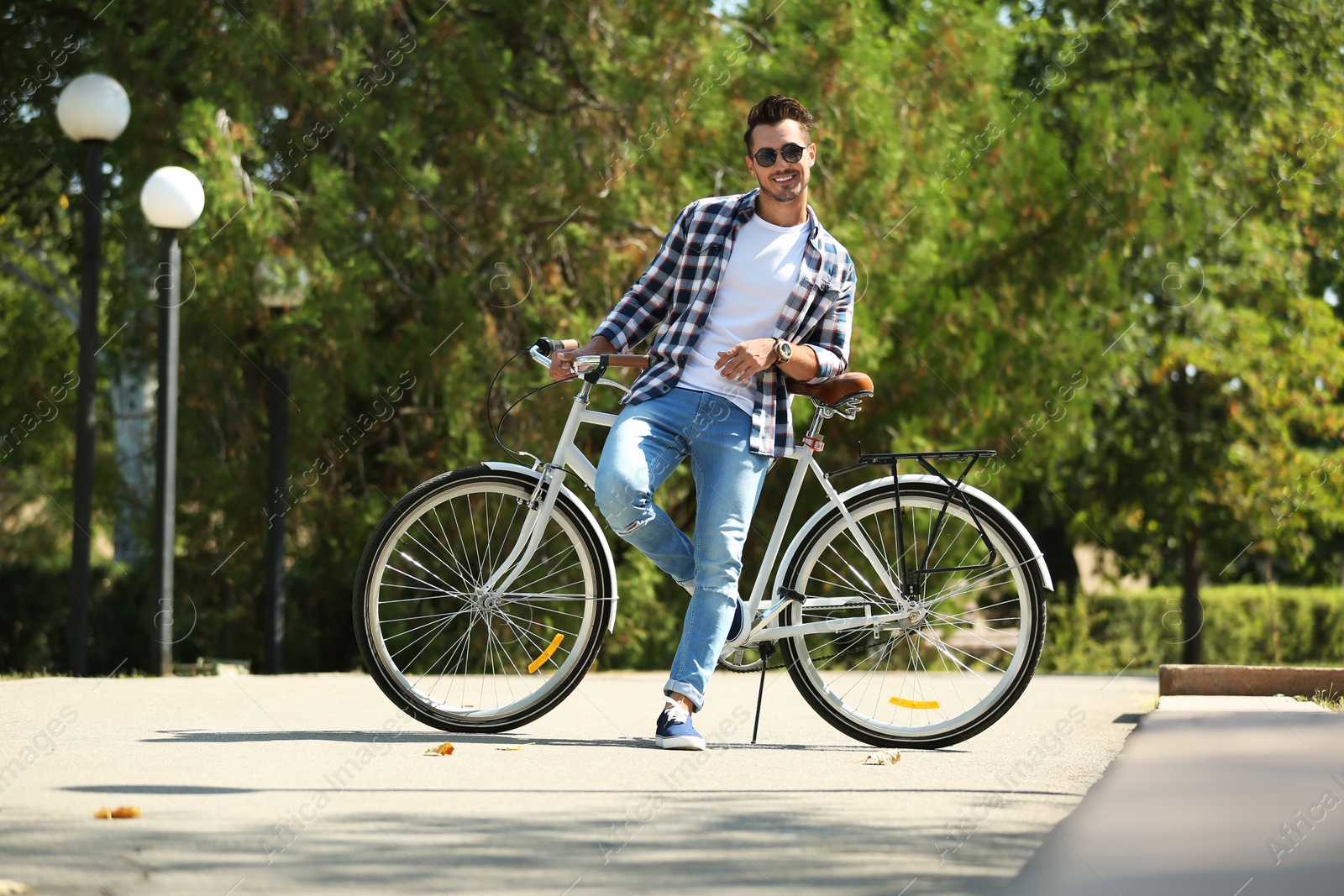 Photo of Handsome young hipster man with bicycle in park