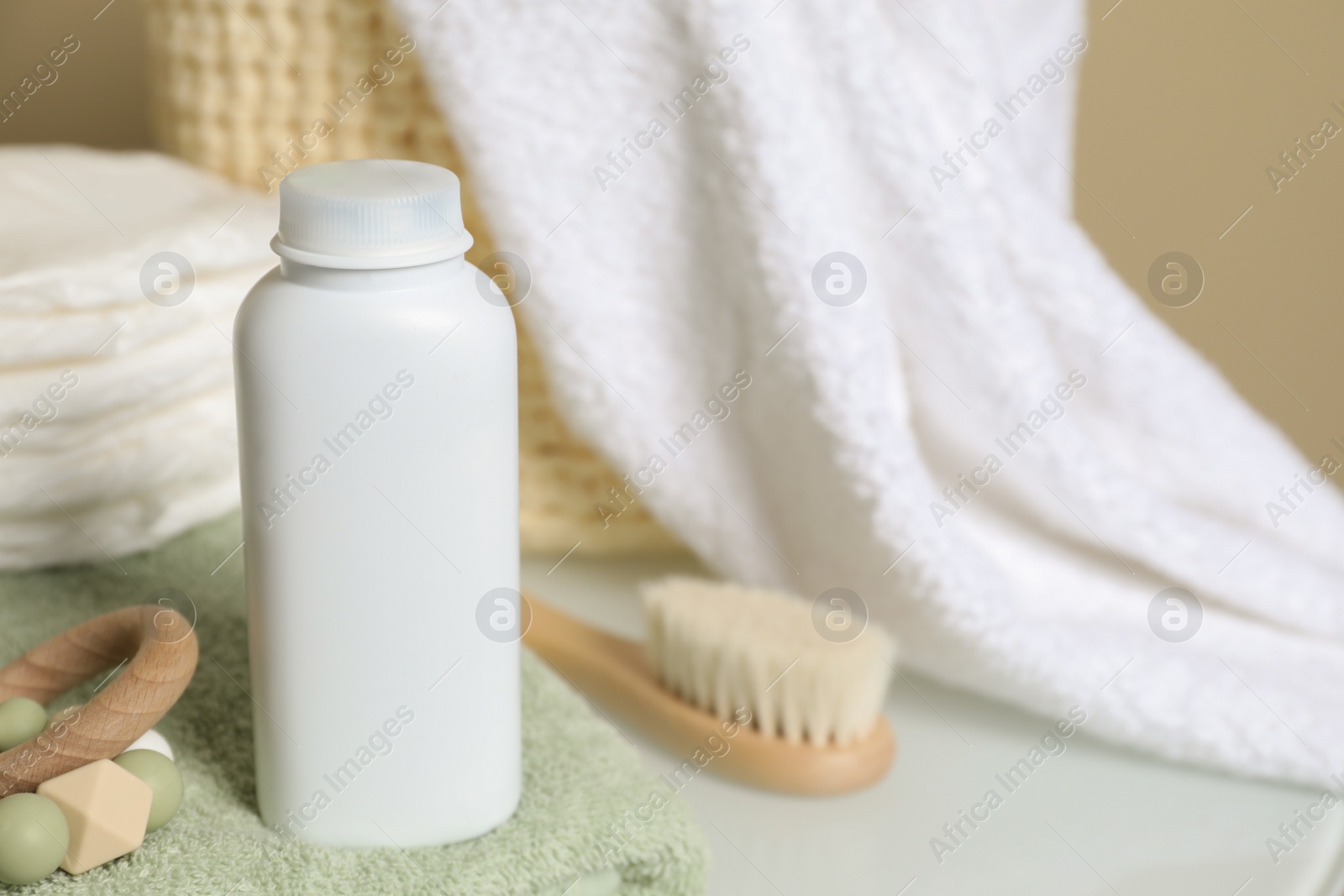 Photo of Bottle of dusting powder, toy and accessories on table, space for text. Baby cosmetic product