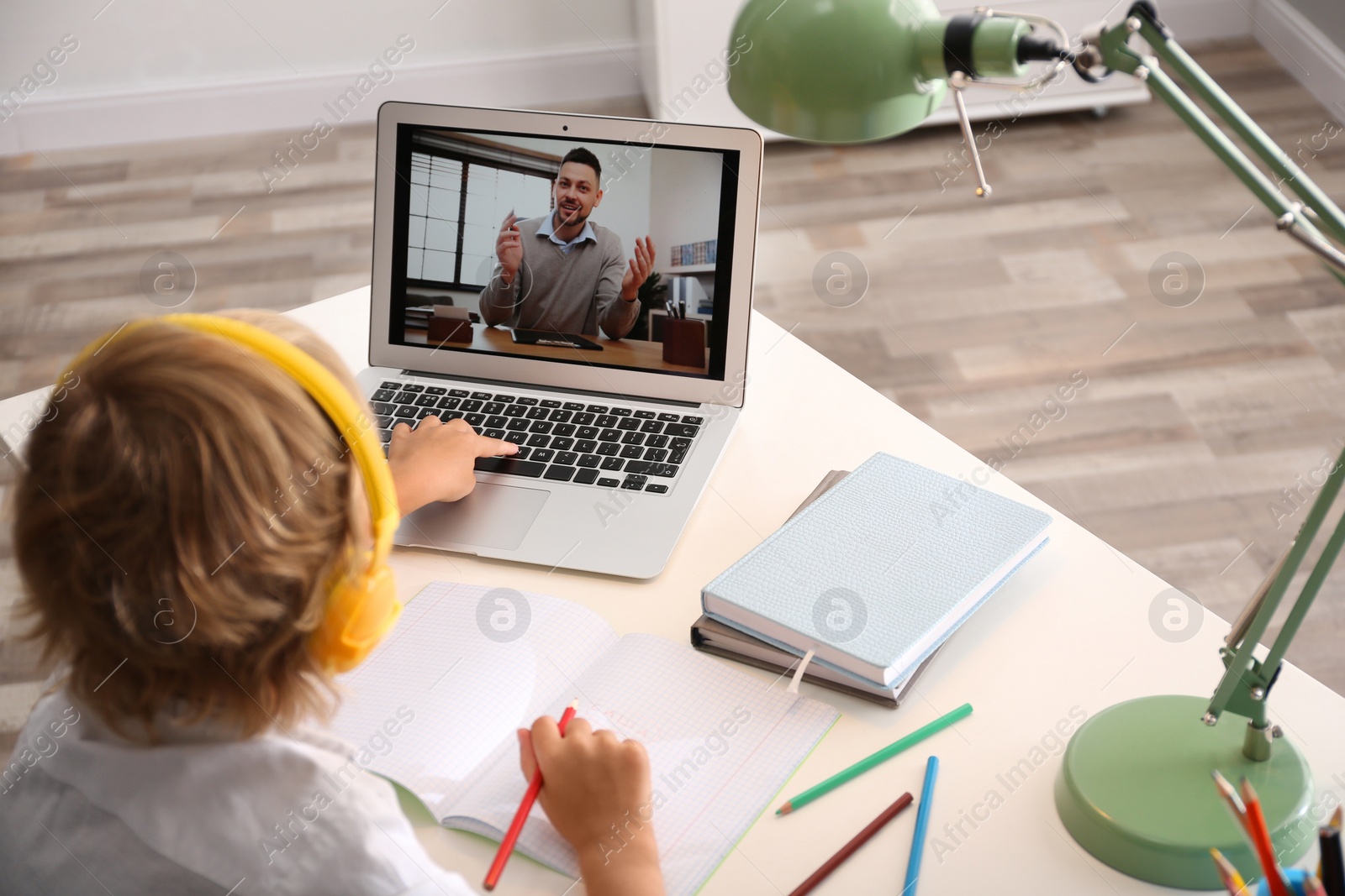 Photo of Little boy studying with teacher via video conference at home. Distance learning during COVID-19 pandemic