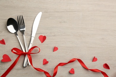 Photo of Cutlery set and red ribbon on background, flat lay with space for text. Valentine's Day dinner