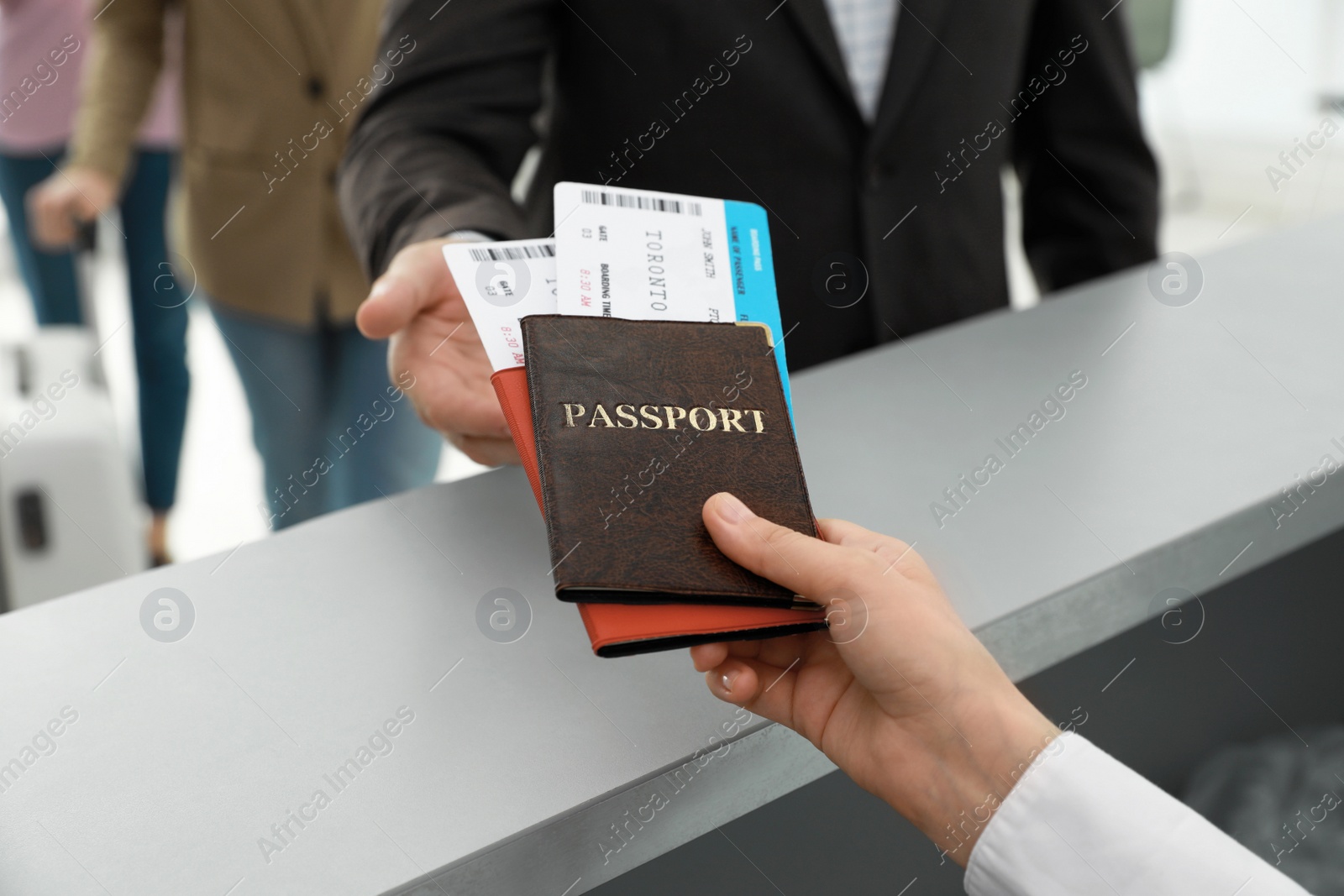 Photo of Agent giving passports and tickets to man at check-in desk in airport, closeup