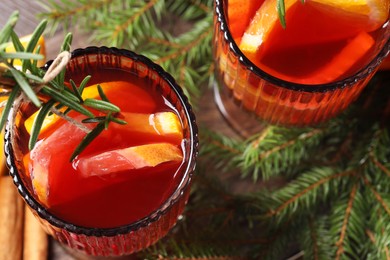 Photo of Christmas Sangria cocktail in glasses, ingredients and fir tree branches on table, closeup