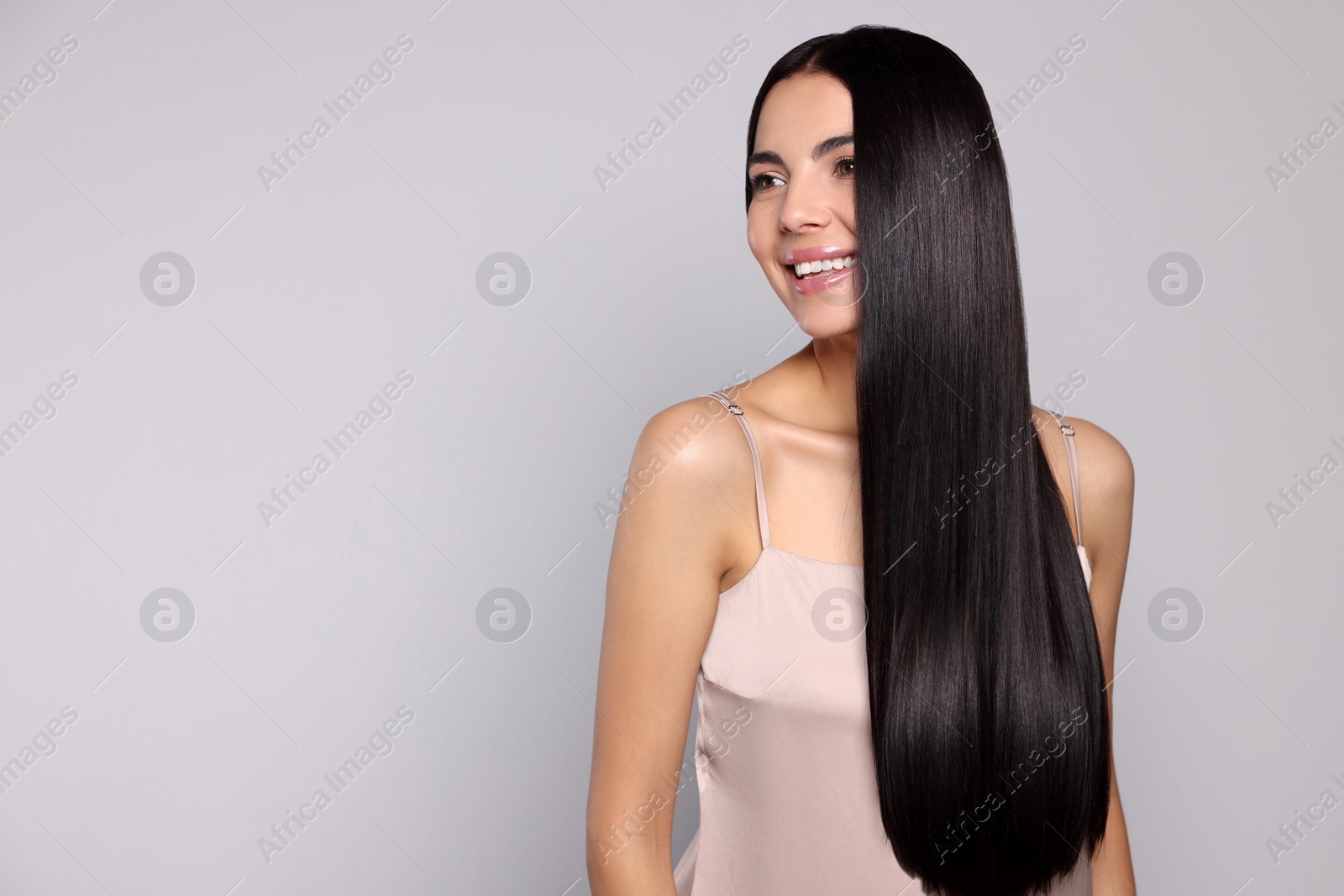 Photo of Portrait of beautiful young woman with healthy strong hair on light grey background, space for text