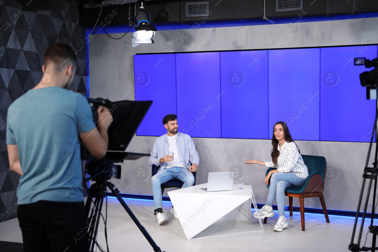 Photo of Presenters and video camera operator working in studio. News broadcasting