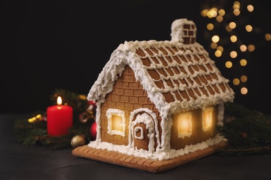 Beautiful gingerbread house decorated with icing on black table