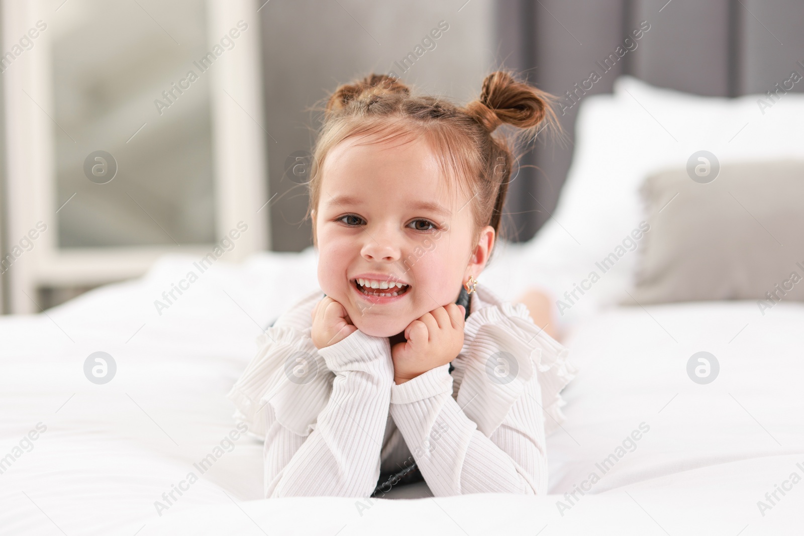 Photo of Portrait of happy little girl on bed indoors
