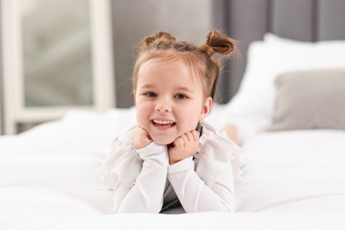 Portrait of happy little girl on bed indoors