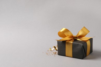 Photo of Beautifully wrapped gift box and confetti on grey background, space for text