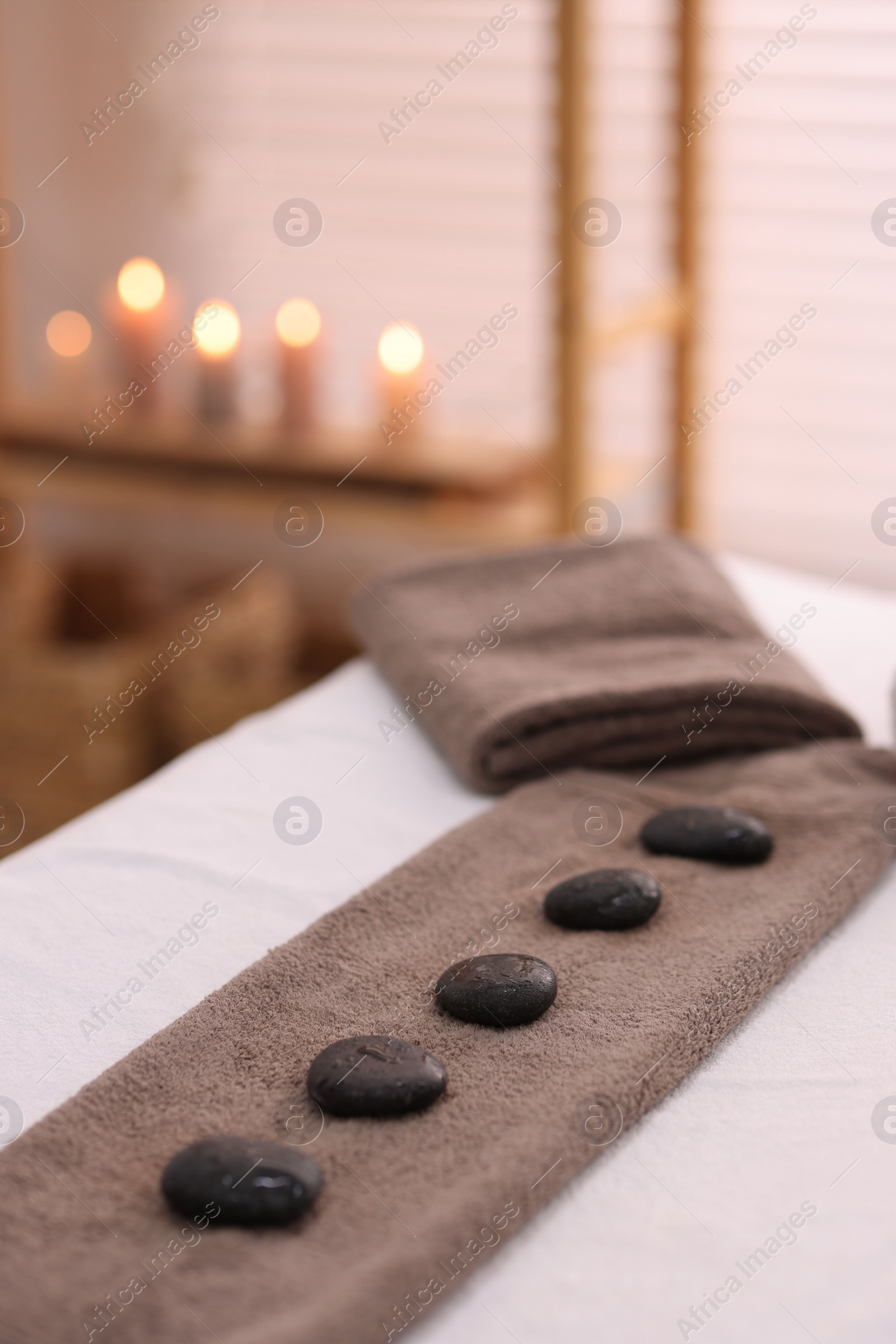 Photo of Towel with arranged spa stones on massage table in recreational center