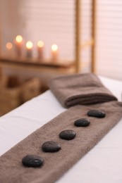 Photo of Towel with arranged spa stones on massage table in recreational center