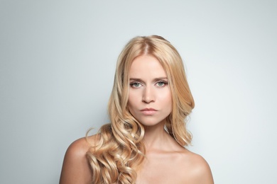 Photo of Beautiful woman with healthy long blonde hair on light background