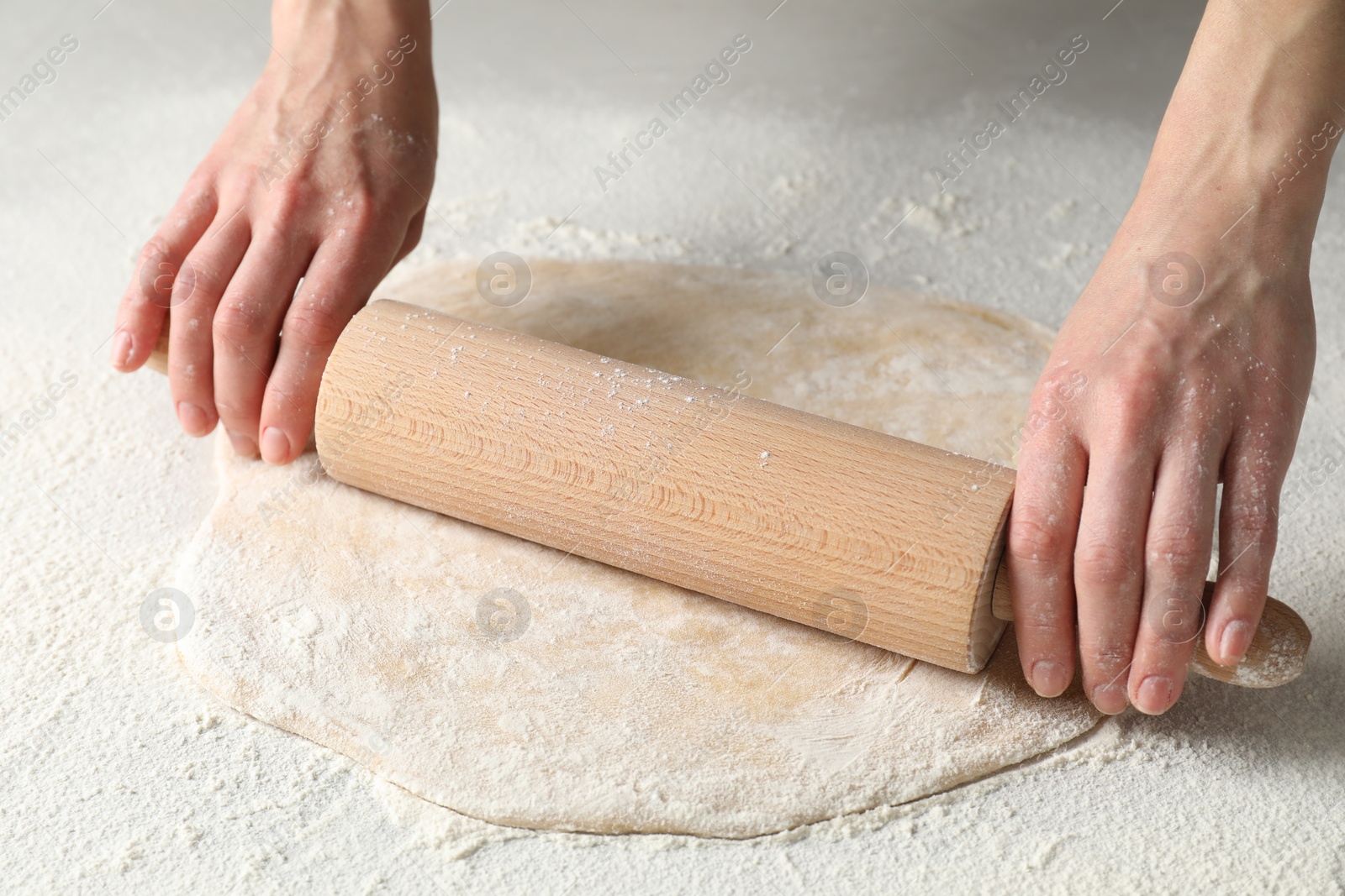 Photo of Woman rolling raw dough at table, closeup