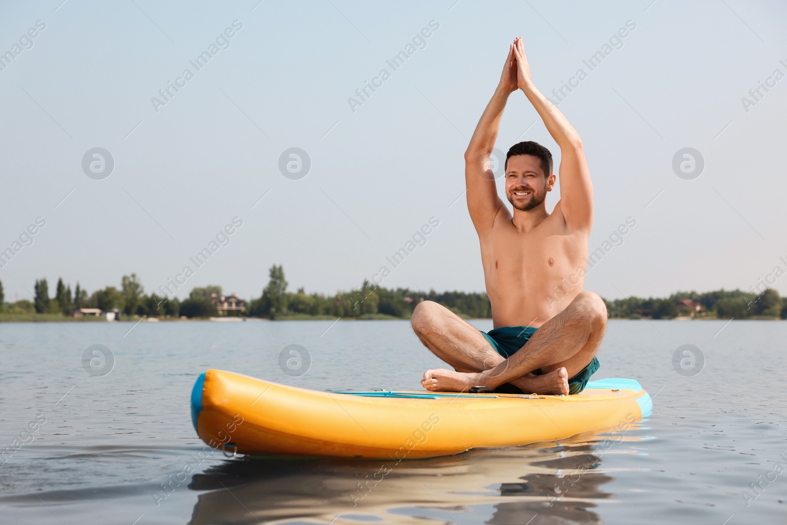 Photo of Man practicing yoga on SUP board on river