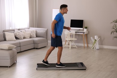 Photo of Sporty man training on walking treadmill at home