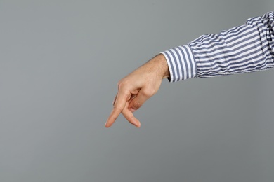 Man imitating walk with hand on grey background, closeup. Finger gesture