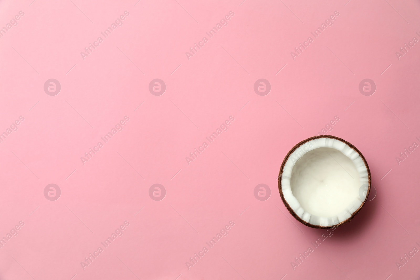 Photo of Fresh coconut half on pink background, top view. Space for text