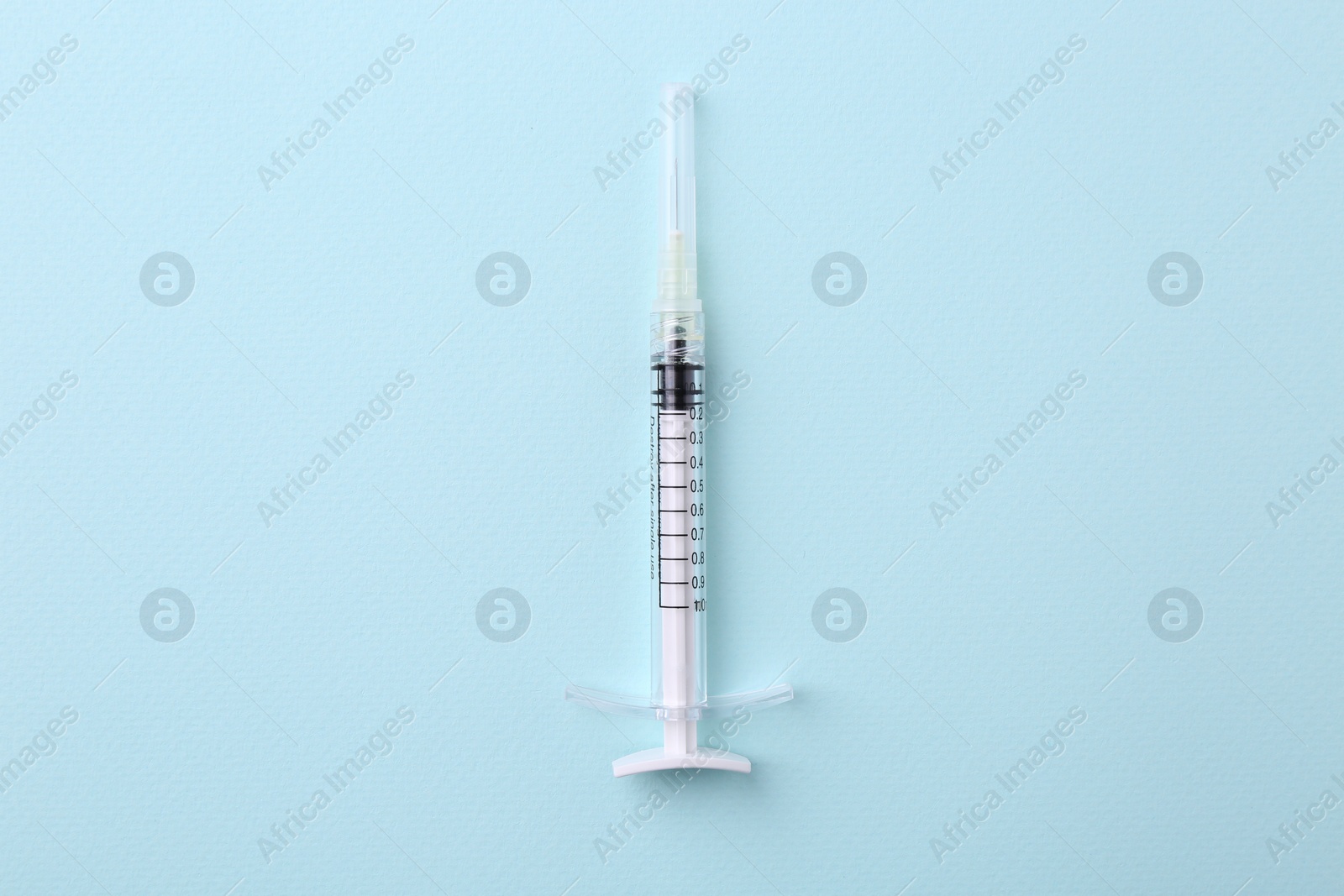 Photo of Cosmetology. Medical syringe on light blue background, top view