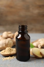 Photo of Ginger essential oil in bottle on light grey table, closeup
