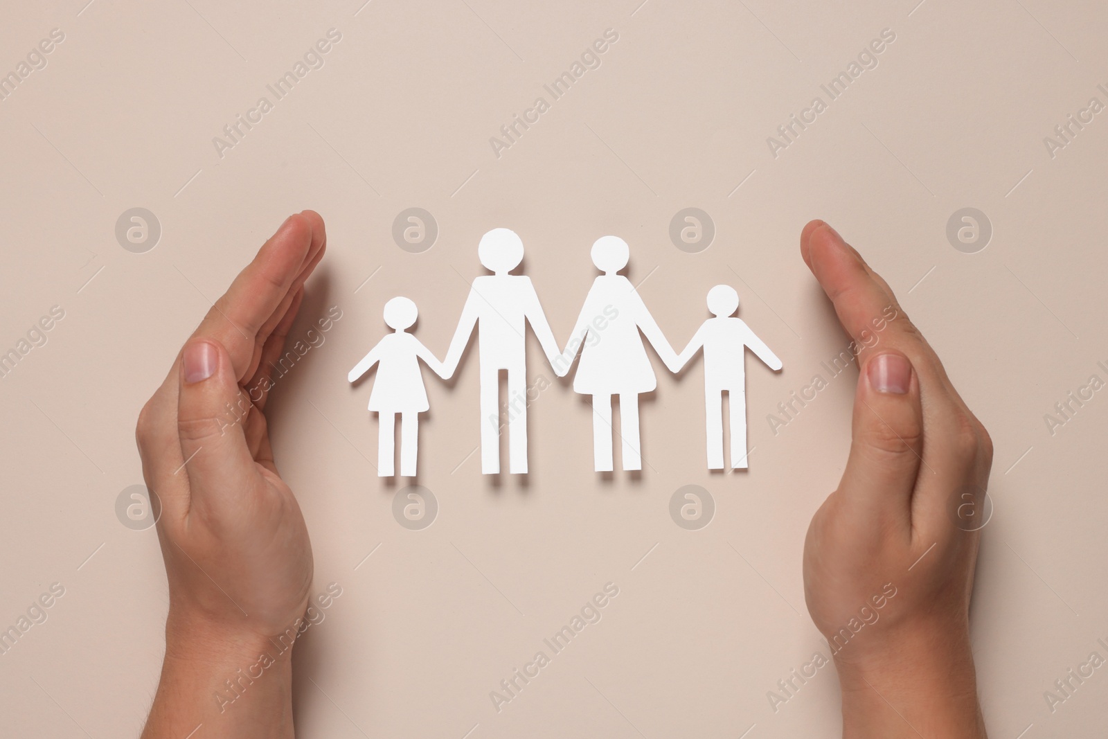 Photo of Man protecting paper family figures on beige background, top view. Insurance concept