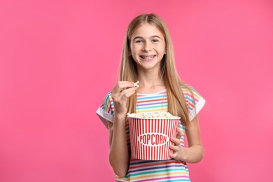 Photo of Teenage girl with popcorn during cinema show on color background