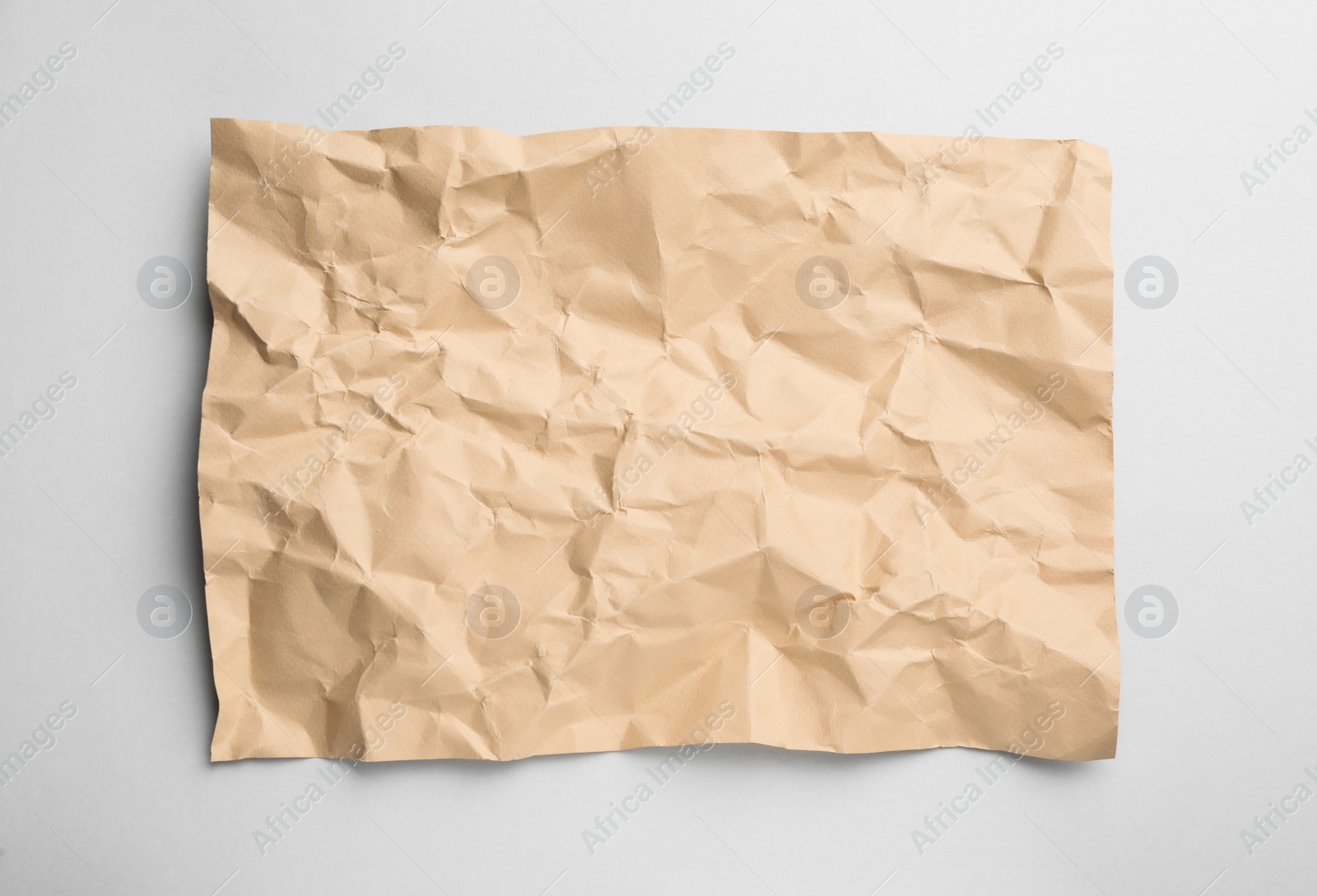 Photo of Sheet of crumpled brown paper on white background, top view