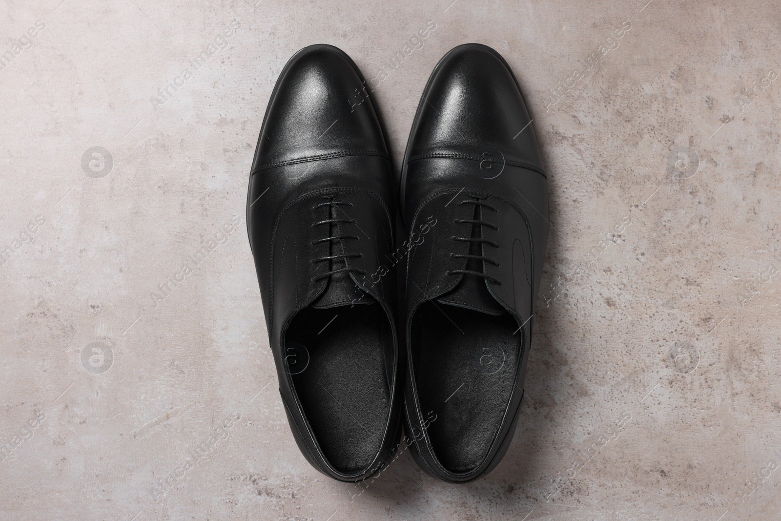 Photo of Pair of black leather men shoes on light grey surface, top view