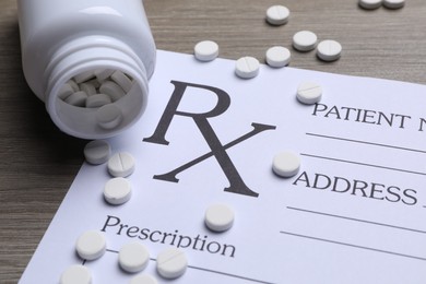 Photo of Medical prescription form, pills and bottle on wooden table, closeup