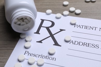 Medical prescription form, pills and bottle on wooden table, closeup