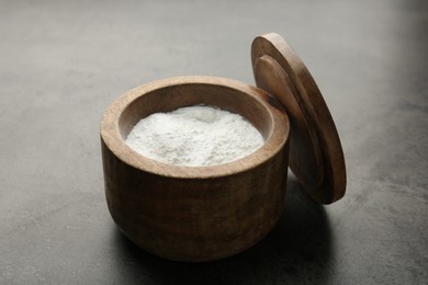 Photo of Baking powder in bowl on grey textured table