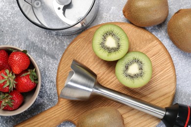 Photo of Hand blender kit and fresh fruits on grey table, top view