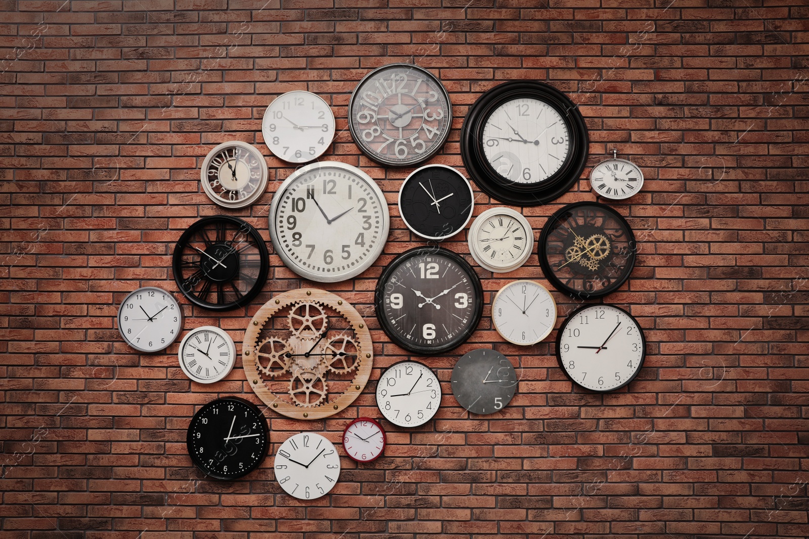 Photo of Collection of clocks hanging on red brick wall