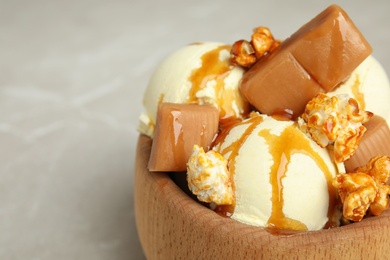 Delicious ice cream served with caramel popcorn and sauce on table, closeup. Space for text