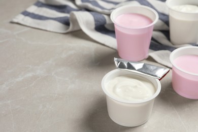 Photo of Plastic cups with delicious organic yogurt on grey marble table, space for text