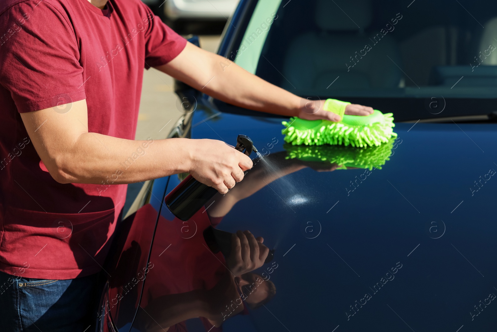 Photo of Man cleaning car hood outdoors, closeup view