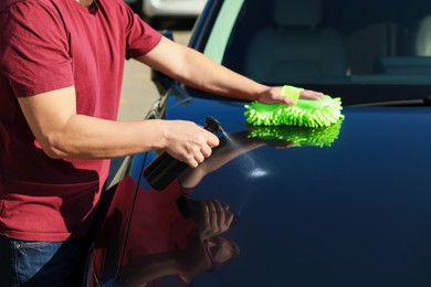 Photo of Man cleaning car hood outdoors, closeup view