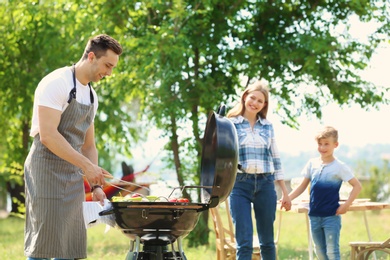 Happy family having barbecue with modern grill outdoors