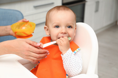 Photo of Young mother feeding her little baby at home