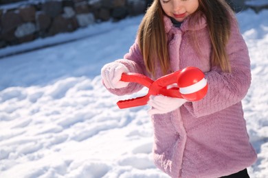 Cute little girl playing with snowball maker outdoors, closeup