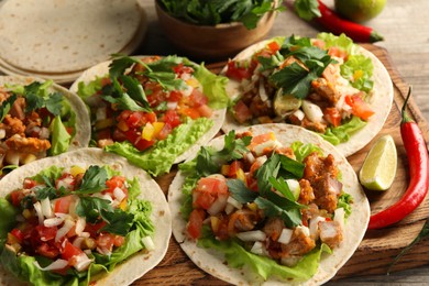 Delicious tacos with vegetables, meat and lime on table, closeup