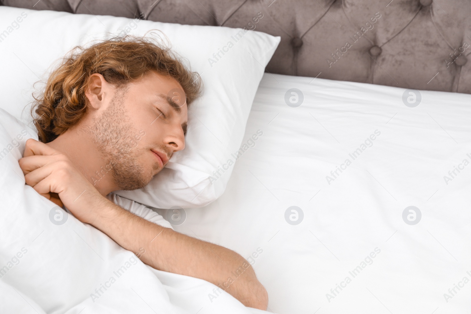 Photo of Handsome young man sleeping on pillow, space for text. Bedtime