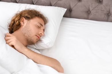 Photo of Handsome young man sleeping on pillow, space for text. Bedtime