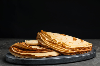 Delicious fresh thin pancakes on grey table