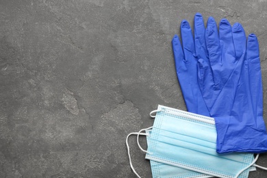 Medical gloves and protective masks on grey background, flat lay. Space for text