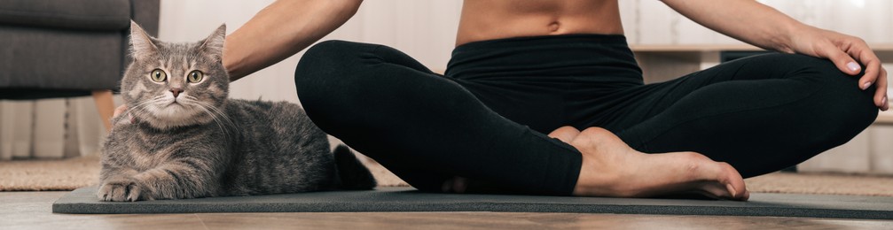 Image of Woman stroking her cat while practicing yoga at home. Horizontal banner design 