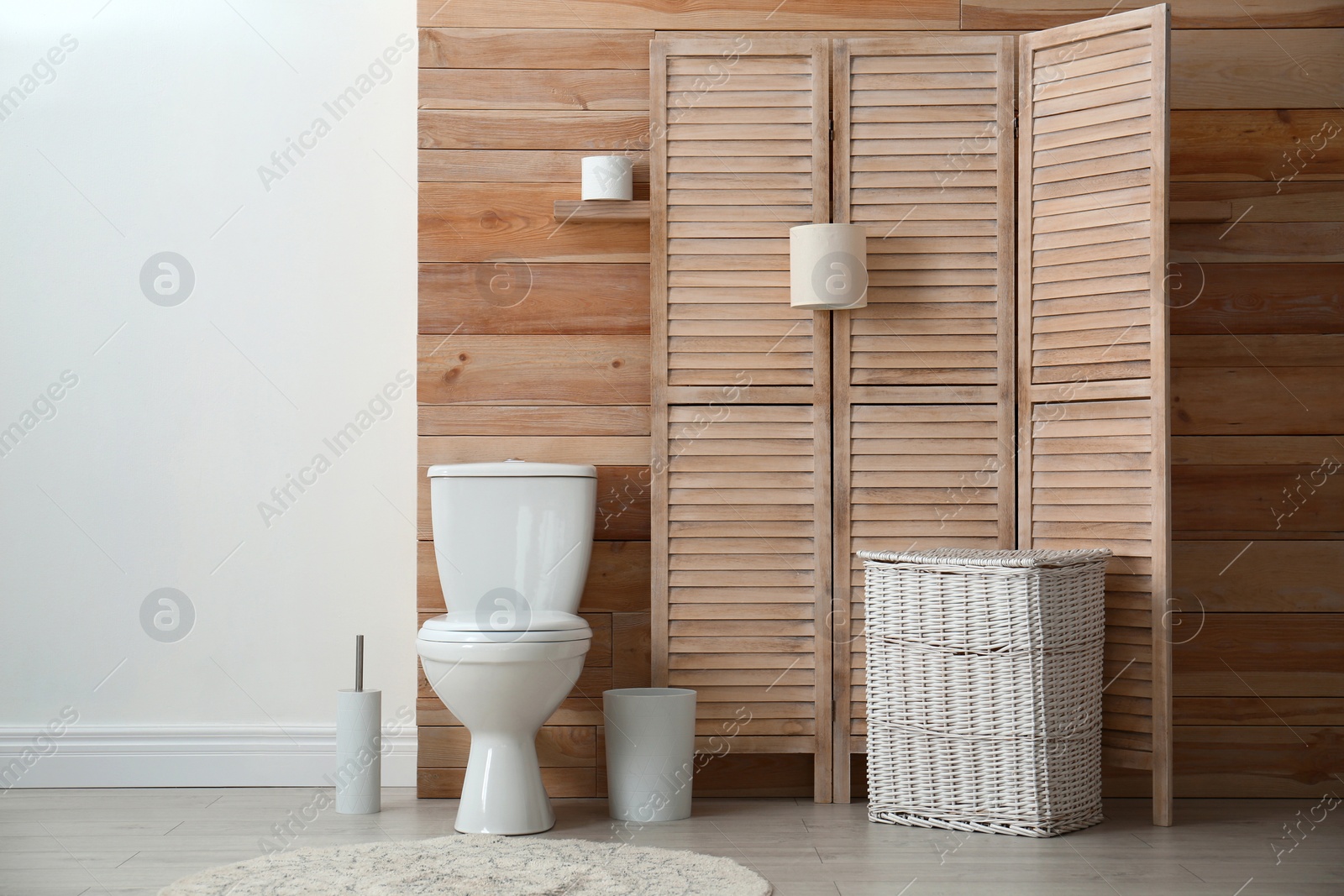 Photo of Toilet bowl near wooden wall in modern bathroom interior