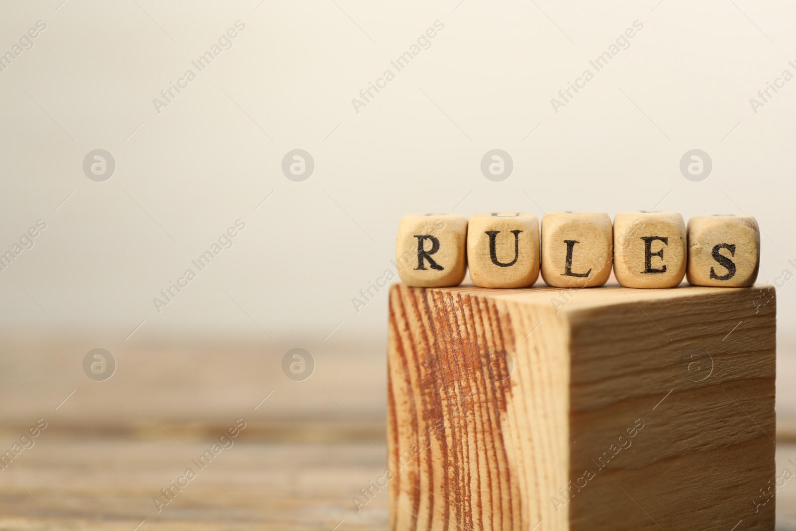 Photo of Word Rules made of cubes with letters on wooden block, space for text